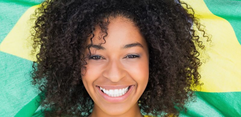 Pretty Girl In Yellow Tshirt Holding Brazilian Flag Smiling At Camera
